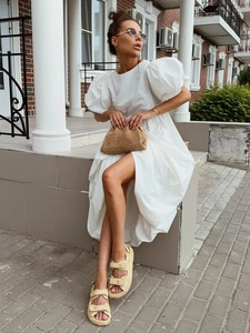 Détail de robe en coton blanc avec manches bouffantes, taille plissée et jupe ample