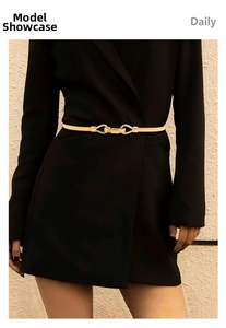Detail of elegant gold metal waist chain with geometric buckle on a black dress