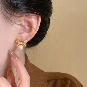 Close-up of 18k gold plated bow stud earring with diamonds and pearl on model
