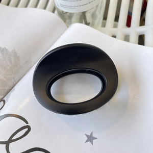Detail shot of a matte black oval claw clip on a magazine for hair styling