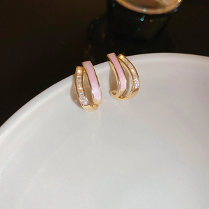 Vue macro de boucles d'oreilles doubles anneaux dorés avec émail rose et zircons