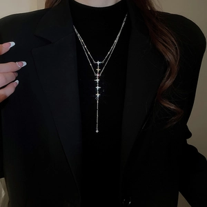 Detail of silver double-layered star necklace with tassel pendant on model's neck