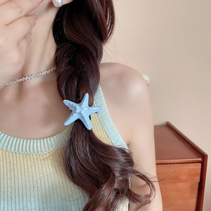 Detailed view of a blue starfish hair clip styled on a braided hairstyle for beach vacations