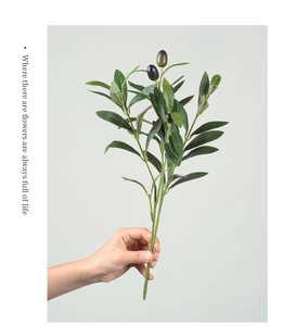 Close-up of lifelike green olive branch with dark fruit for wedding home decor