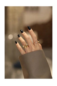 Detailed view of hand wearing a gold butterfly ring set with a pink oval gemstone