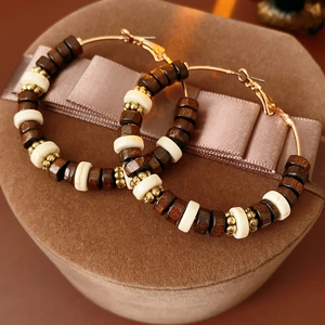 Macro view of Bohemian round hoop earrings with wooden beads on brown velvet box