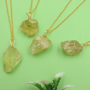 Detail of four handmade natural green crystal stone necklaces with gold wire wrapping