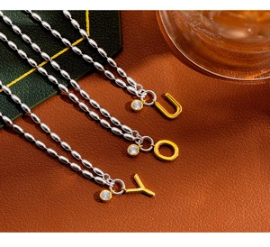 Close-up of three S925 silver beaded bracelets with gold letter pendants and zircon stones