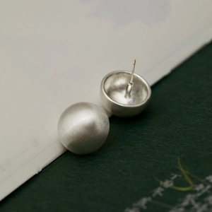 Detailed macro view of silver brushed metal ball earrings with professional pin structure