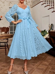 Détail d'une robe en dentelle bleu clair avec col en V, manches ajourées et ceinture à nœud