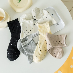 Vue à plat de chaussettes en coton à pois dans les tons beige, gris et jaune