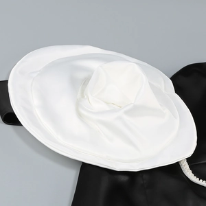 Détail de robe en satin noir avec grand col à volants blancs et bordure de perles