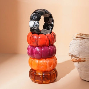 Vertical stack of colorful geometric acrylic bangles with marble ink texture on a warm background