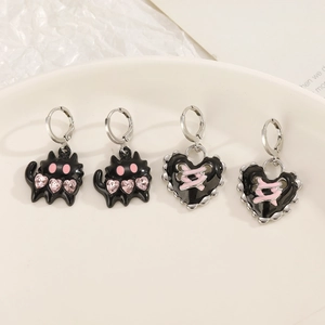 Detailed macro shot of gothic black cat and pink heart pendants on silver hoop earrings