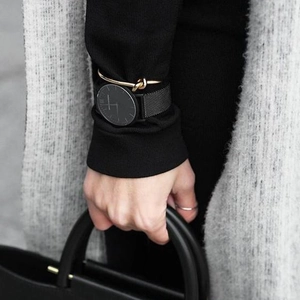 Black Milanese loop watch paired with a stylish gold-toned knot cuff bracelet