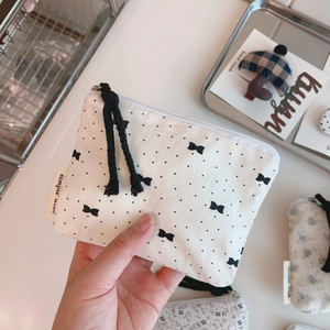 Close-up of a small floral canvas coin purse with zipper and simple wish label detail