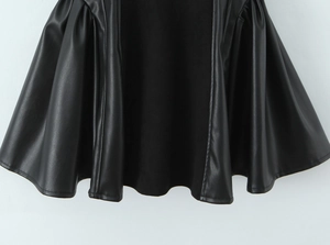 Detail shot of the black PU leather pleated hem showing fine texture and stitching