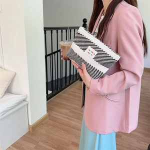 Detail showing woven black and white striped cosmetic bag with colorful embroidered logo
