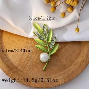 Close-up of green leaf brooch with white pearl showing dimensions 3.1cm and 6.1cm