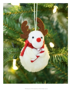 Close-up of plush reindeer ornament with red scarf and candy cane on a Christmas tree