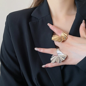 Macro detail of large gold and silver ginkgo leaf rings with brushed metal texture