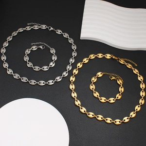 Polished gold and silver coffee bean link necklace and bracelet set on black background