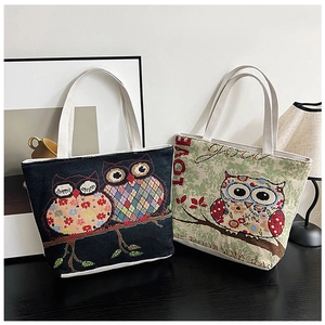 Detailed view of two ethnic canvas tote bags with cartoon owl embroidery and dual handles