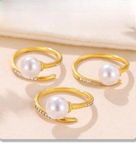 Macro detail of three PVD gold plated rings with white pearls and micro-pave zircons