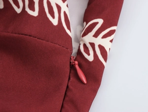 Macro shot of an invisible zipper on a deep red ethnic print dress with leaf patterns
