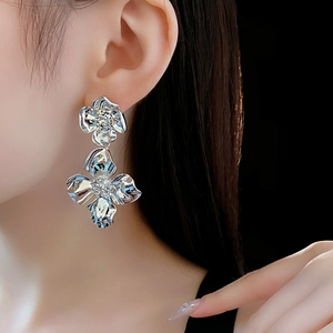 Macro view of silver floral drop earrings on ear with high-gloss metallic finish