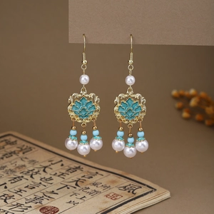 Detail of Chinese style earring featuring butterfly pearls and green enamel on vintage book