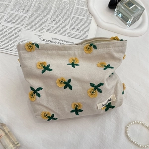 Détail d'une broderie de tournesol sur une trousse de maquillage en toile avec étiquette tissée