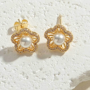 Close-up of gold flower stud earrings with white pearl and sparkling cubic zirconia stones