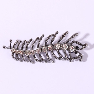 Détail d'une broche mille-pattes en métal sombre sertie de strass brillants et cristaux