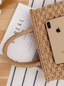 Handwoven straw tote bag in light camel on a rustic wooden table for summer vacation look