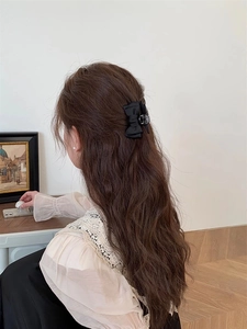 Détail d'une pince à cheveux en satin noir avec nœud papillon sur les cheveux d'une femme