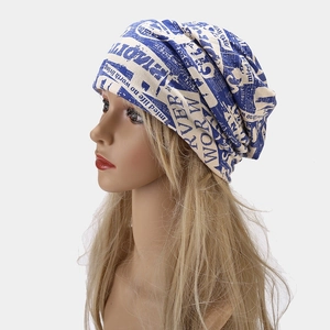 Close-up of newspaper print pattern on blue and white knitted slouchy beanie hat