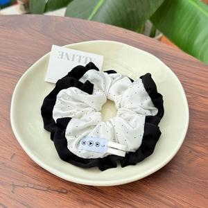 Close-up of a retro polka dot scrunchie with black ruffled edges in a decorative dish
