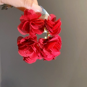 Detail of red tiered fabric flower earrings showing soft petal texture and hanging design