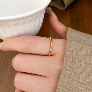 Detailed view of gold plated rainbow zircon ring worn by hand holding a ceramic mug