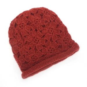 Close-up of handmade red crochet knit hat featuring 3D floral patterns and ribbed edge