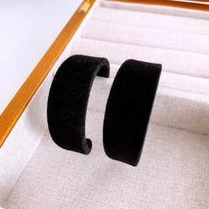 Gros plan de boucles d'oreilles C larges en velours noir dans une boîte à bijoux