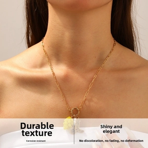 Dettaglio di una collana dorata con ciondoli a forma di uva e stivale su catena a maglie