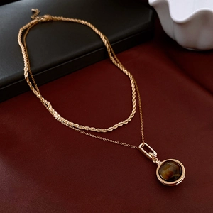 Detail of double-layer gold necklace with twisted rope chain and tiger eye stone pendant