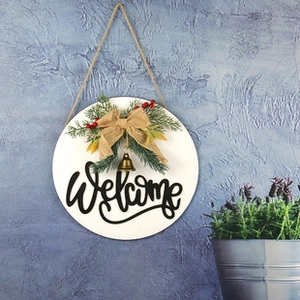 Detail of wooden welcome sign featuring pine branches, red berries and burlap bow
