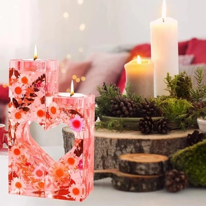 Dettaglio di portacandele in resina a forma di cuore con fiori secchi e candele