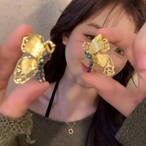Close-up of golden hollow butterfly earrings with vintage filigree texture on a model