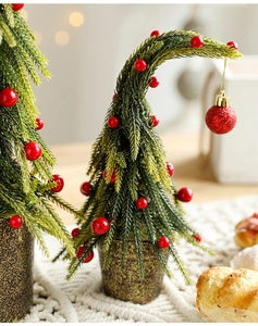 Close-up of mini snow-flocked Christmas tree with red berries and golden base