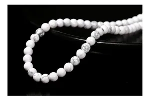 Macro shot of natural matte white howlite beads with grey veins on a black ceramic plate