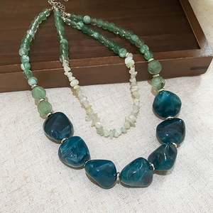 Detail of double-layer beaded necklace featuring green natural stones and blue resin beads